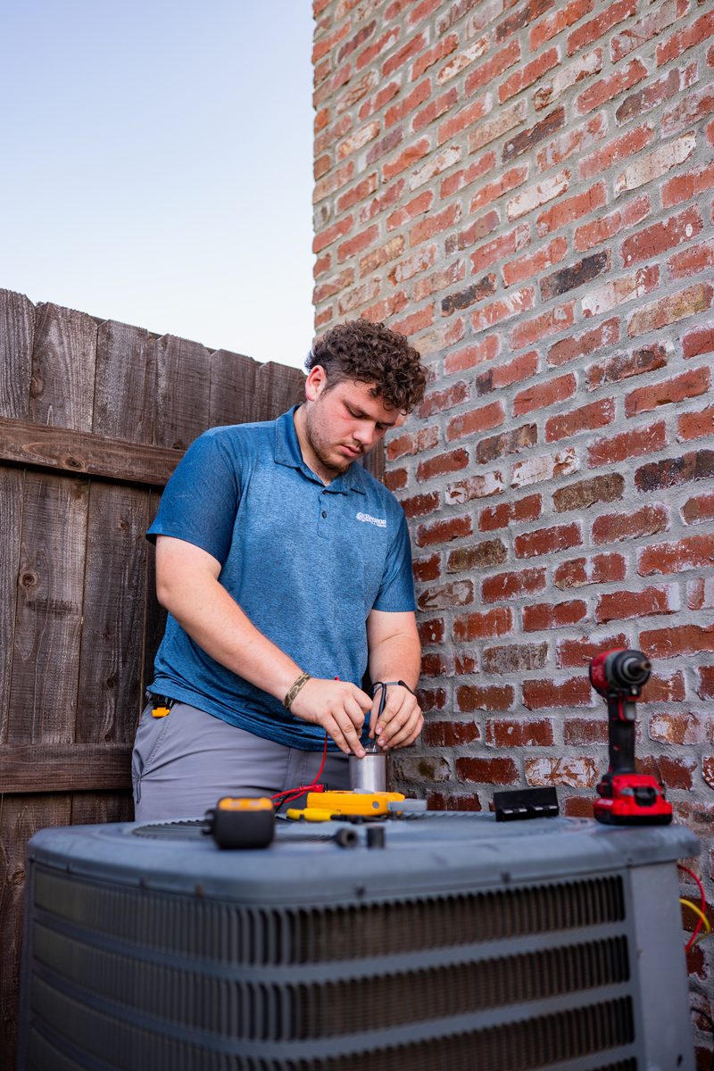 Superior Heating & Cooling technician servicing a residential condenser during a maintenance visit