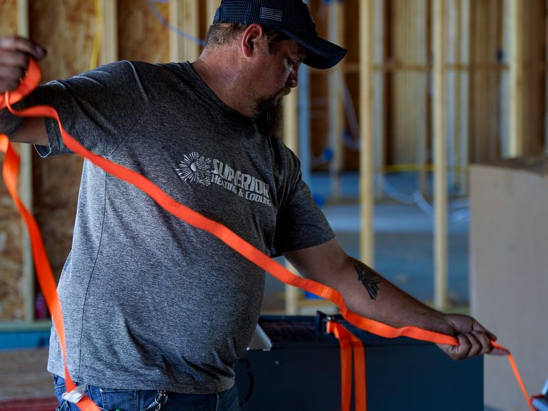 Installer strapping down an air handler on a new-construction job