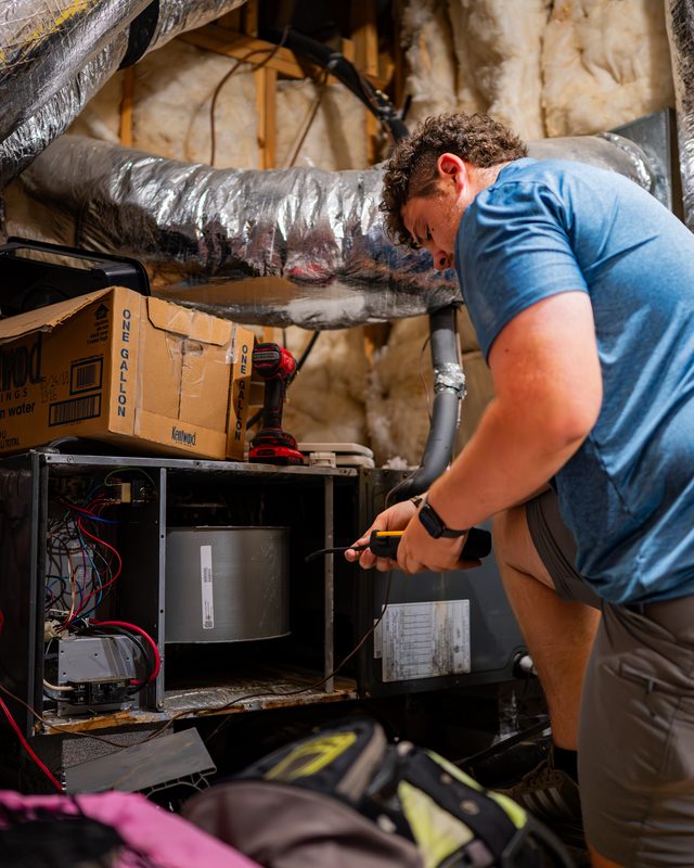 Technician servicing an air handler in an attic