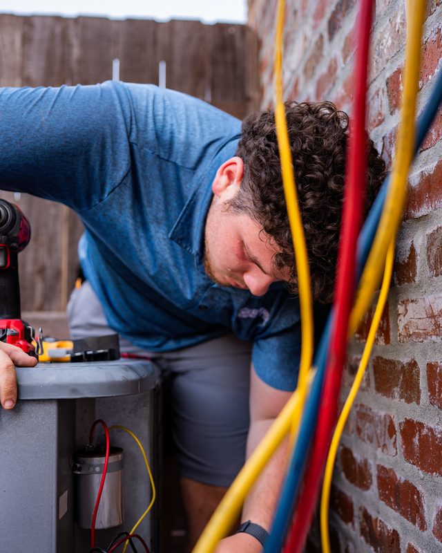 Technician connecting refrigerant gauges to a residential condenser