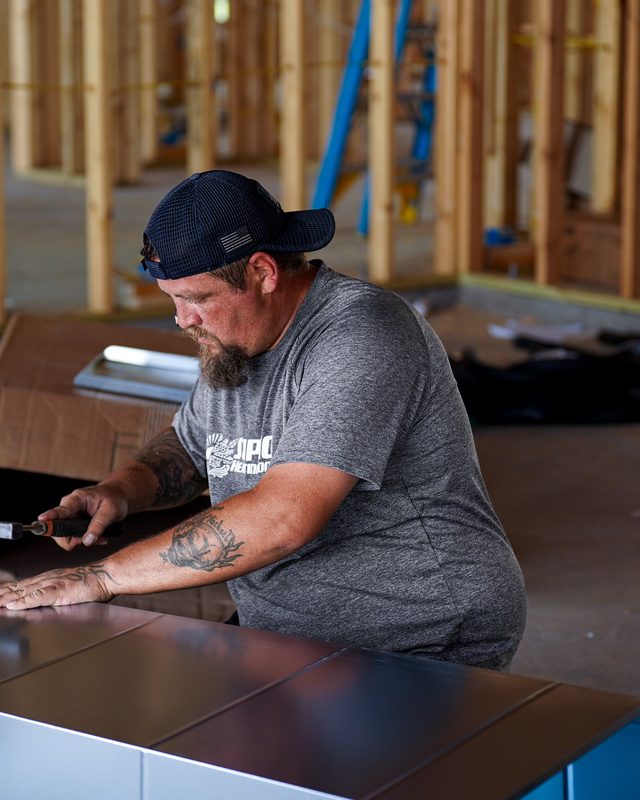 Installer assembling a sheet-metal duct plenum on a new-construction job